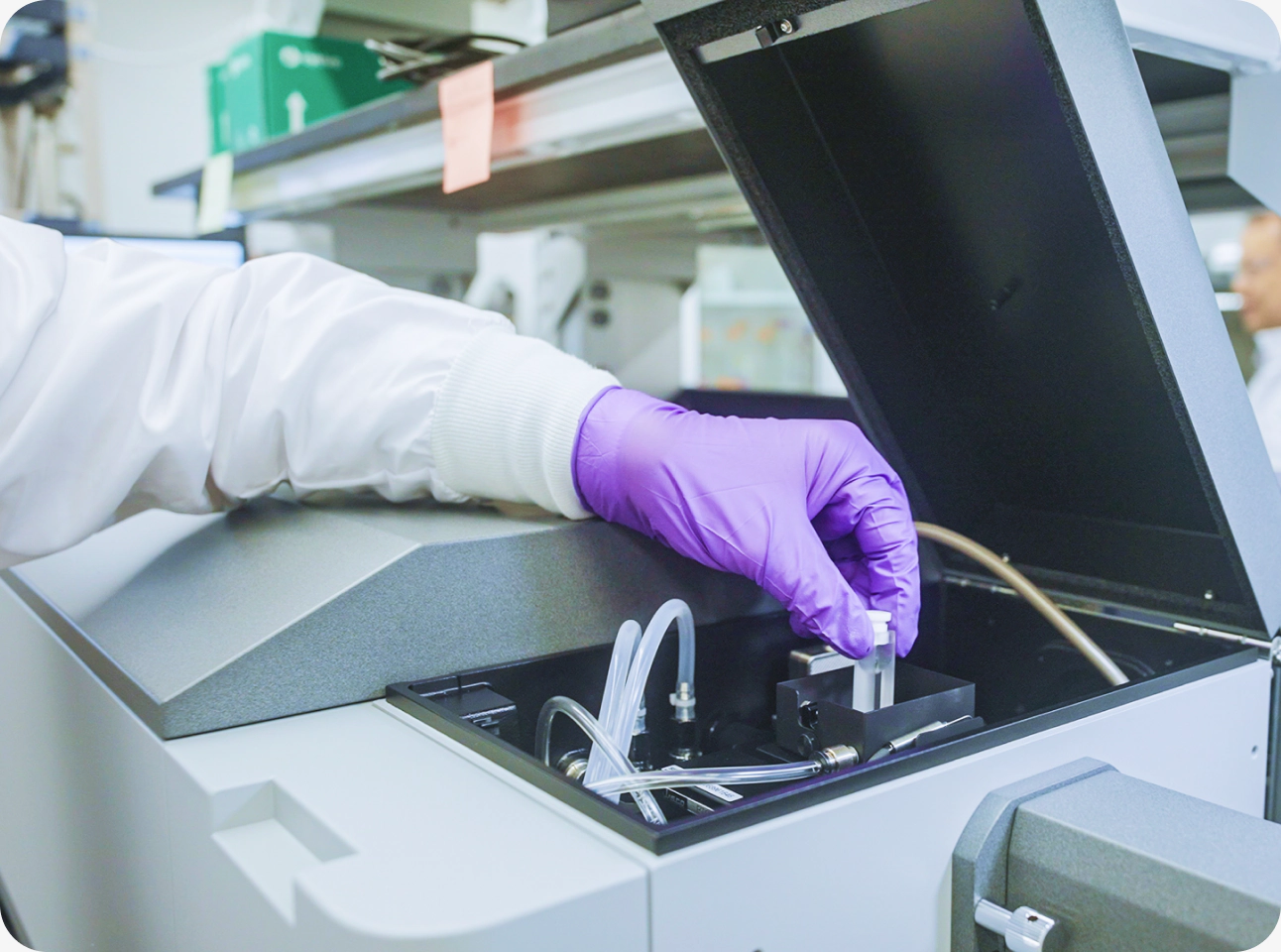 A gloved technician loading a sample into analytical laboratory equipment