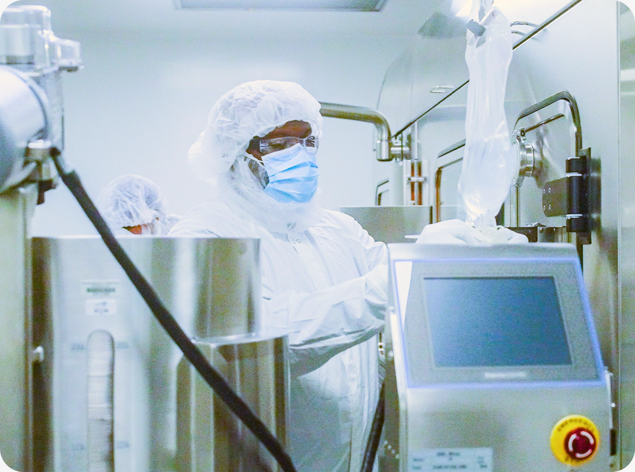 A technician operating pharmaceutical manufacturing equipment in a cleanroom